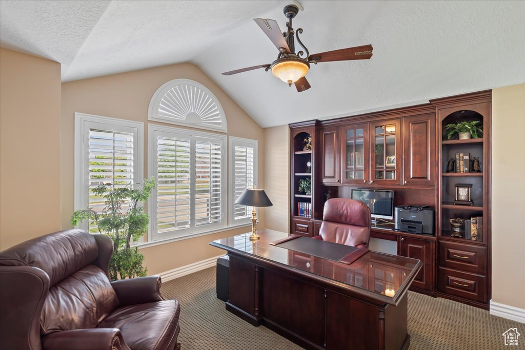 Office area featuring light colored carpet, a ceiling fan, lofted ceiling, baseboards, and healthy amount of natural light