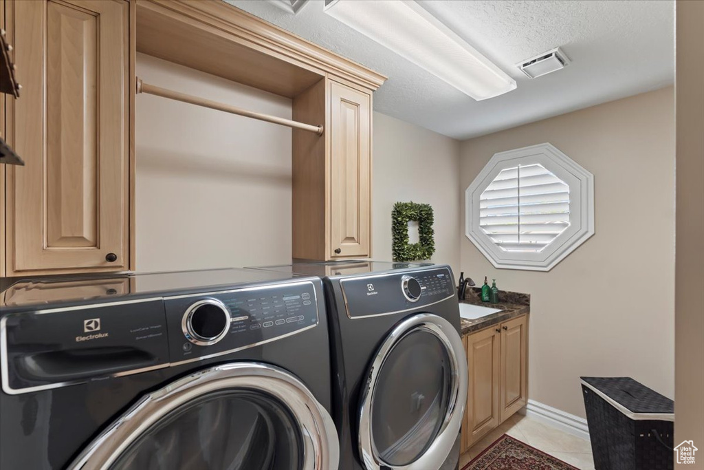 Washroom with separate washer and dryer, cabinet space, light tile patterned flooring, a textured ceiling, and baseboards