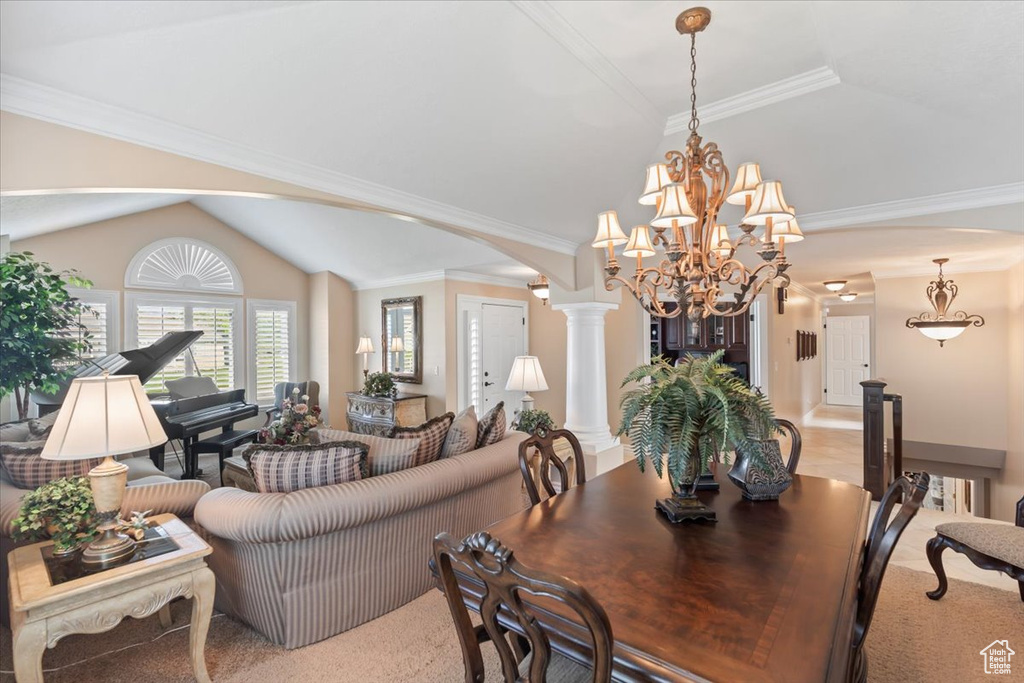 Dining space with lofted ceiling, a chandelier, decorative columns, light carpet, and arched walkways
