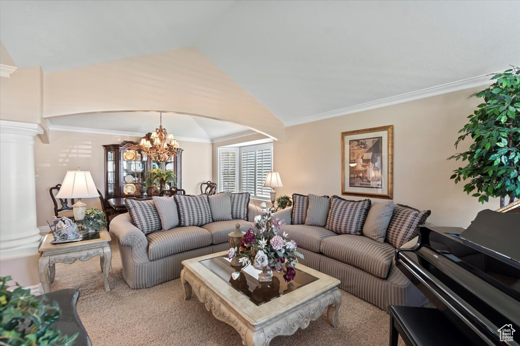 Living room with a chandelier, decorative columns, crown molding, arched walkways, and lofted ceiling
