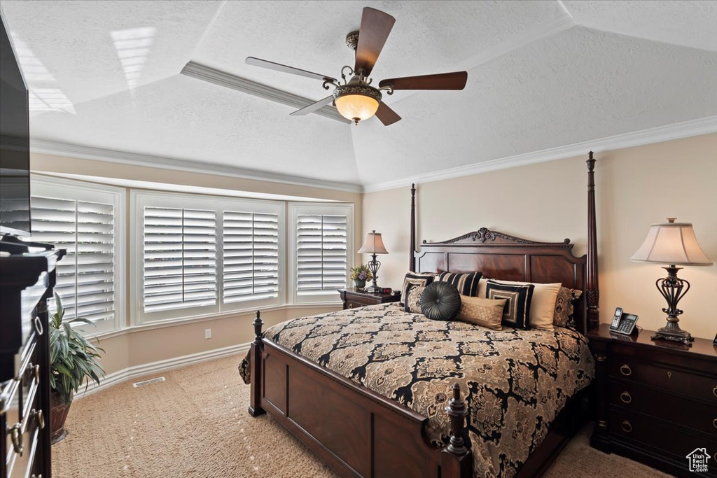 Carpeted bedroom with a textured ceiling, baseboards, ceiling fan, vaulted ceiling, and ornamental molding