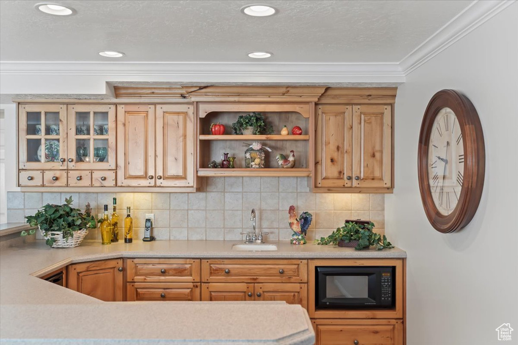 Indoor wet bar featuring black microwave, ornamental molding, and tasteful backsplash
