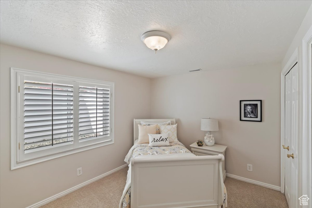 Carpeted bedroom featuring baseboards and a textured ceiling