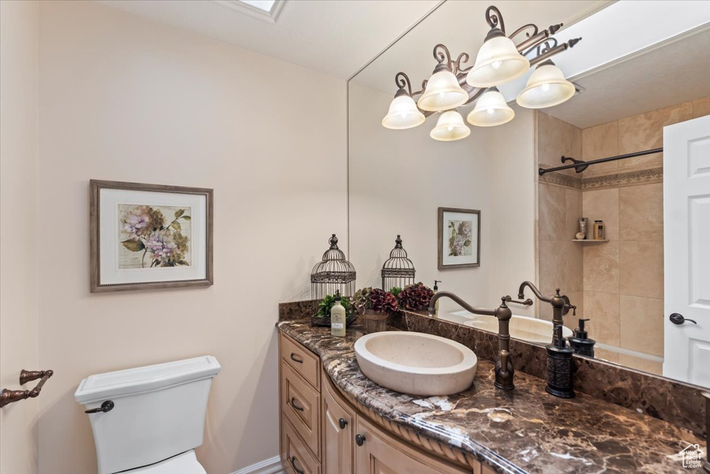 Bathroom with vanity, toilet, a chandelier, and a shower