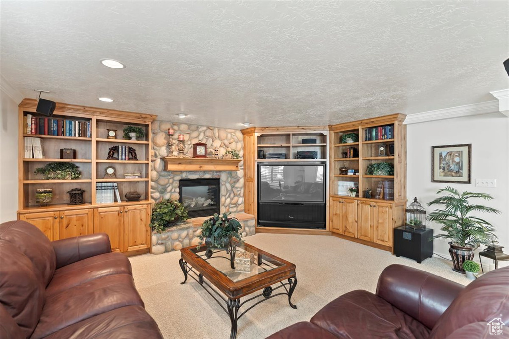 Carpeted living room featuring crown molding, a stone fireplace, and a textured ceiling
