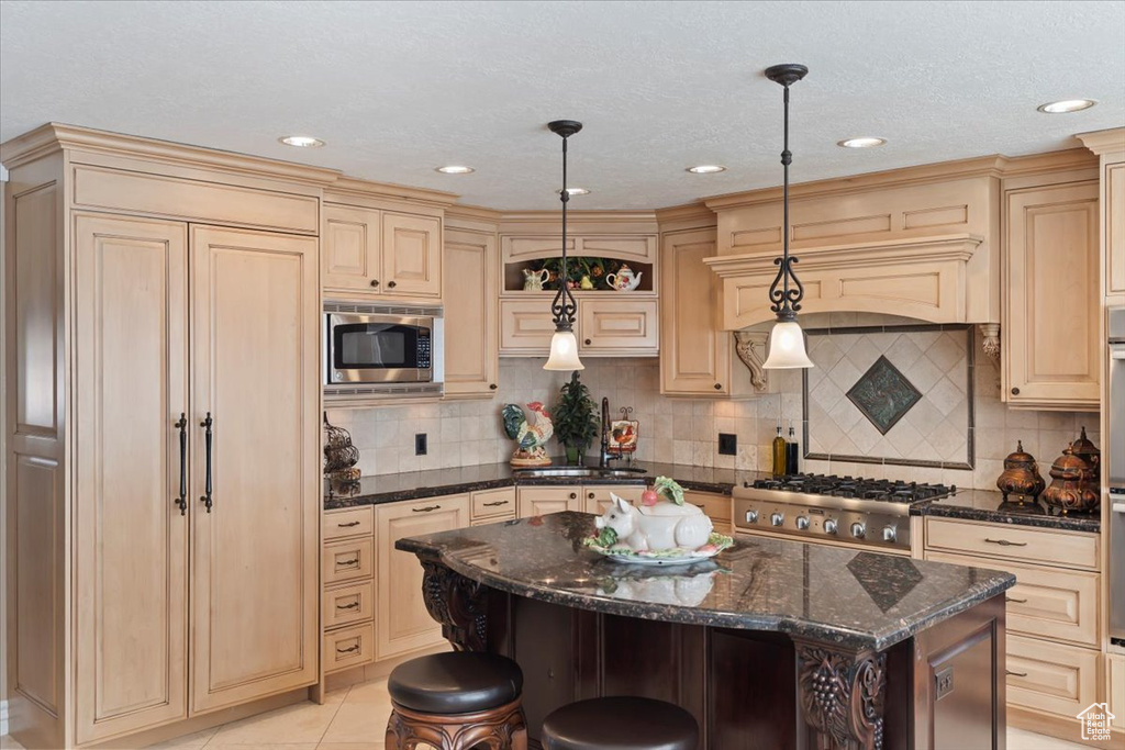 Kitchen with appliances with stainless steel finishes, cream cabinets, a kitchen breakfast bar, and recessed lighting