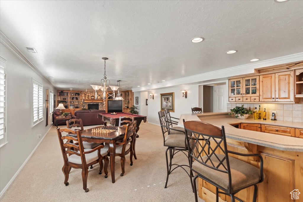 Dining room featuring crown molding, baseboards, light carpet, bar area, and a chandelier