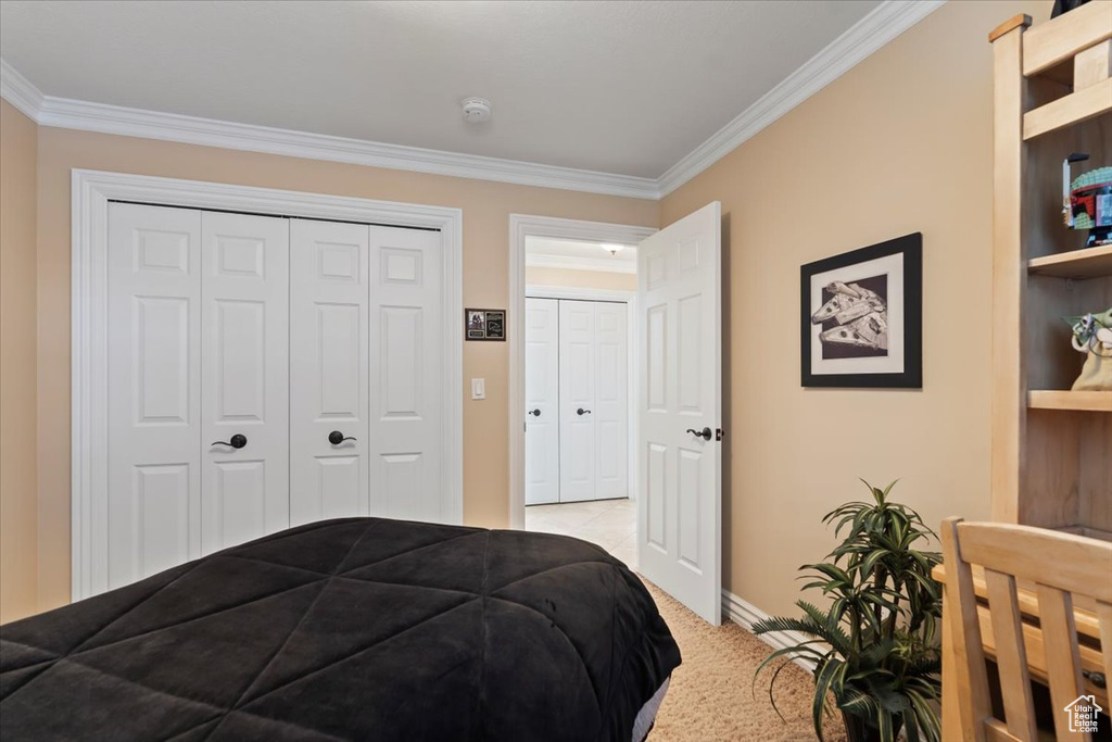 Bedroom with crown molding, baseboards, a closet, and light carpet