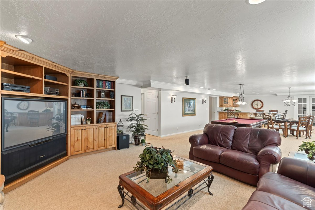 Living area with light colored carpet, a textured ceiling, crown molding, and baseboards