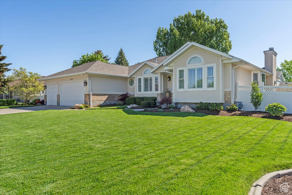 Ranch-style house featuring a chimney, a garage, stucco siding, and driveway
