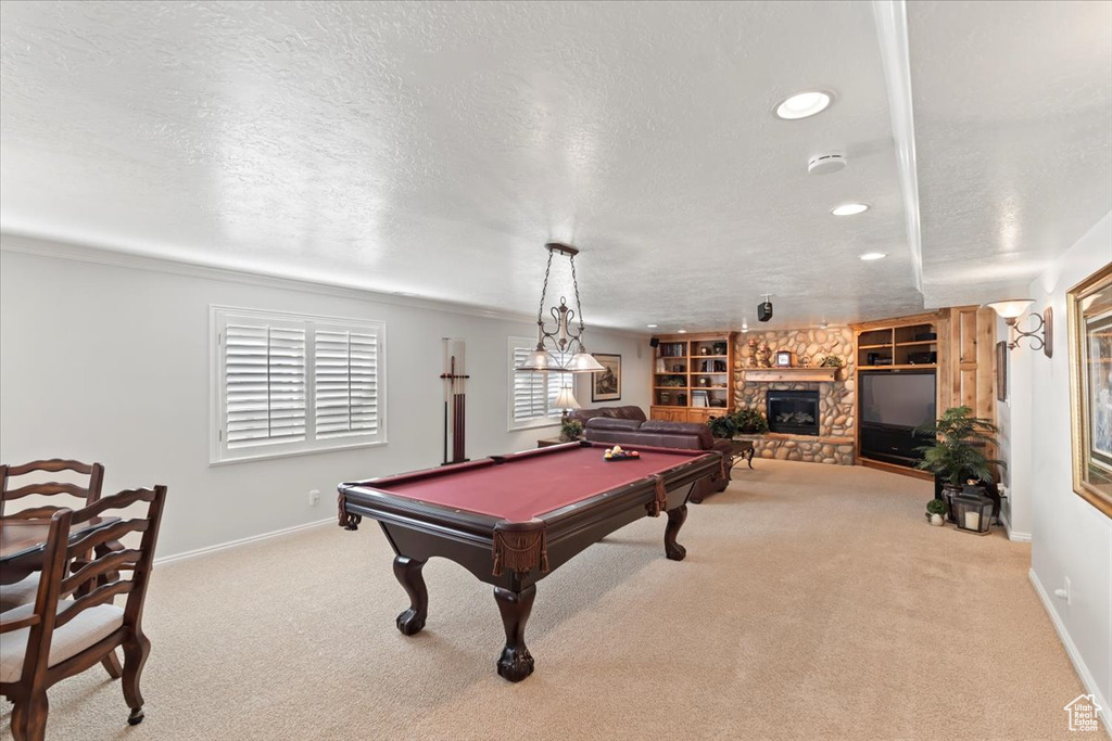 Rec room with a textured ceiling, baseboards, a stone fireplace, carpet, and recessed lighting