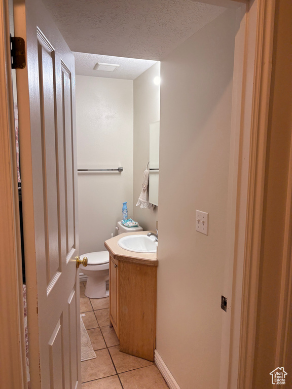 Half bath featuring tile patterned floors, vanity, toilet, and a textured ceiling
