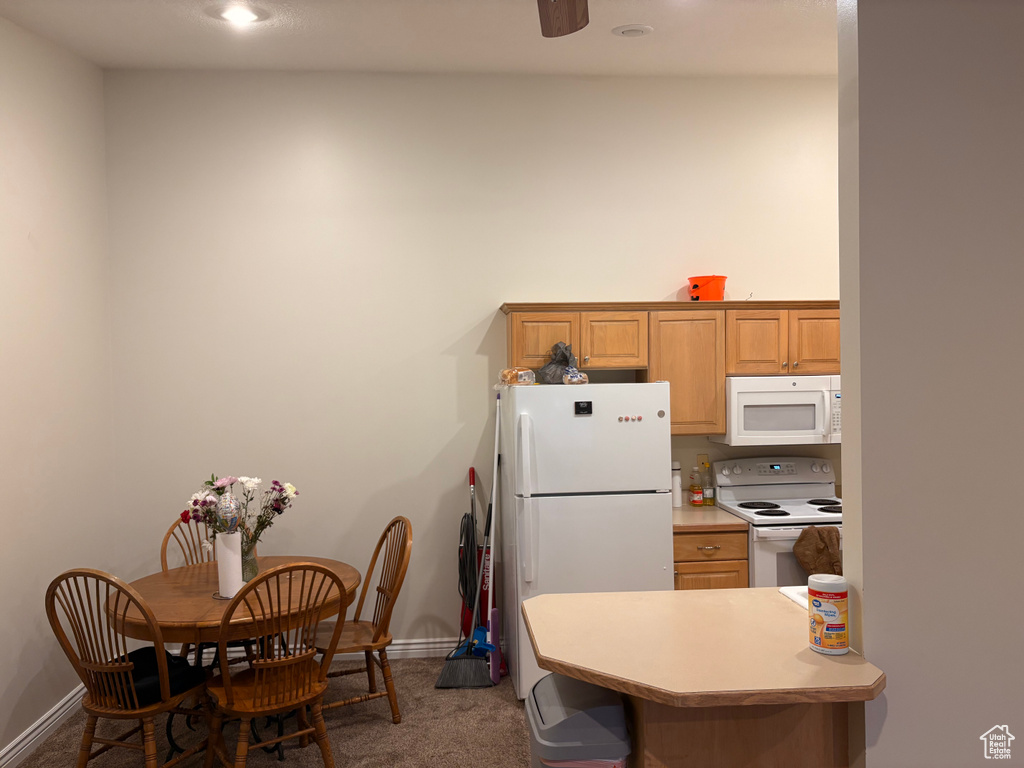 Kitchen with white appliances, dark carpet, baseboards, light countertops, and recessed lighting