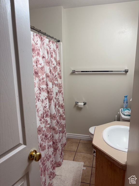 Bathroom featuring tile patterned floors, vanity, toilet, curtained shower, and baseboards
