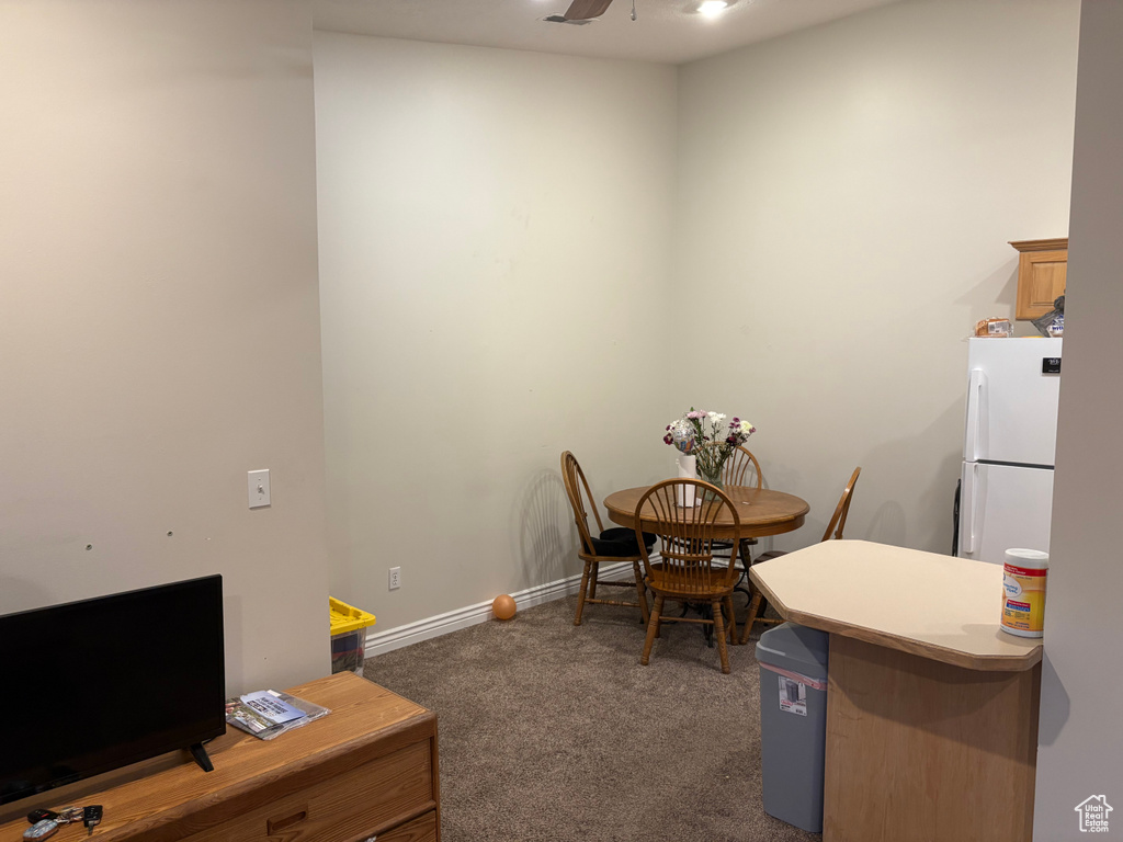 Carpeted dining area with ceiling fan and baseboards