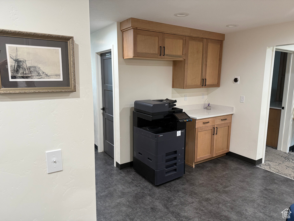 Kitchen with baseboards, brown cabinets, light countertops, and dark flooring
