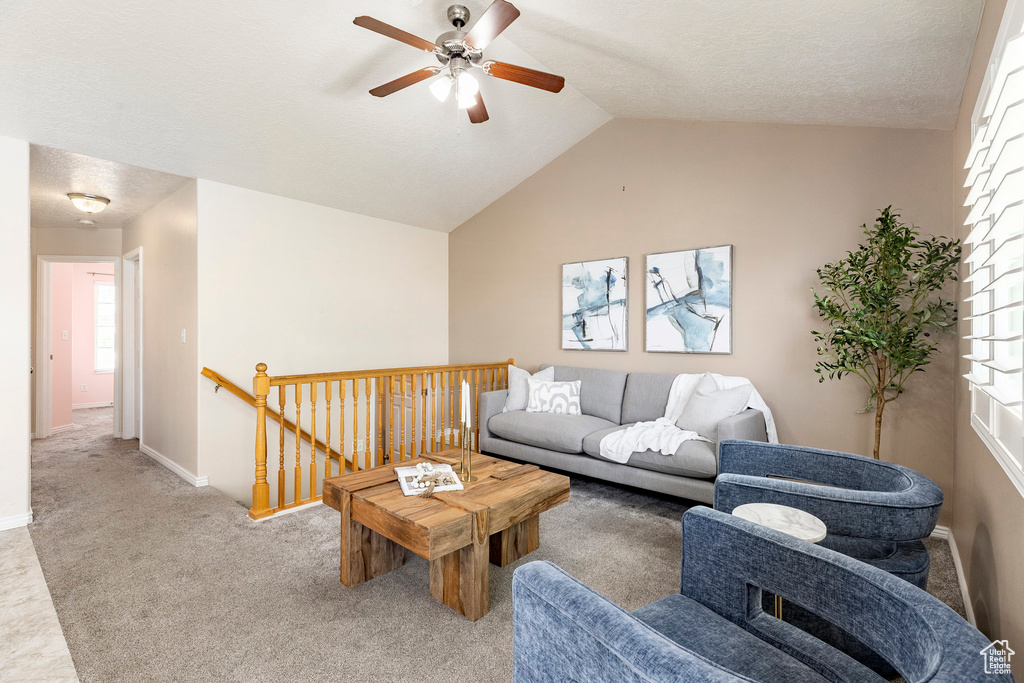 Living area with a ceiling fan, carpet flooring, lofted ceiling, and baseboards