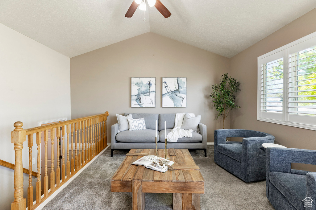 Living area with carpet, a ceiling fan, and lofted ceiling
