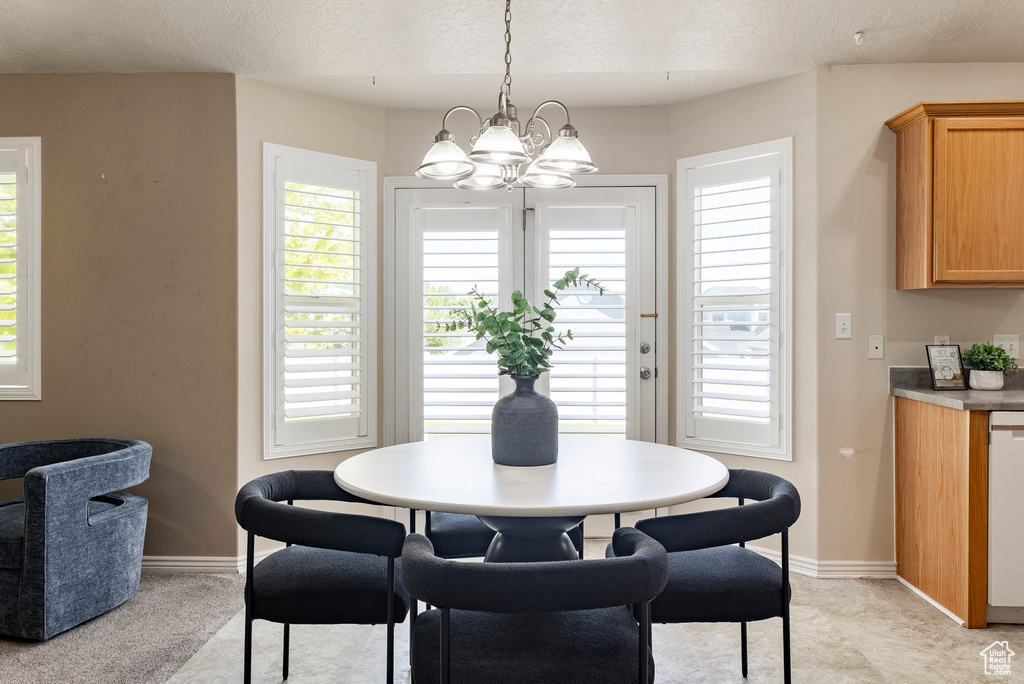 Dining space featuring a chandelier, a textured ceiling, healthy amount of natural light, and baseboards