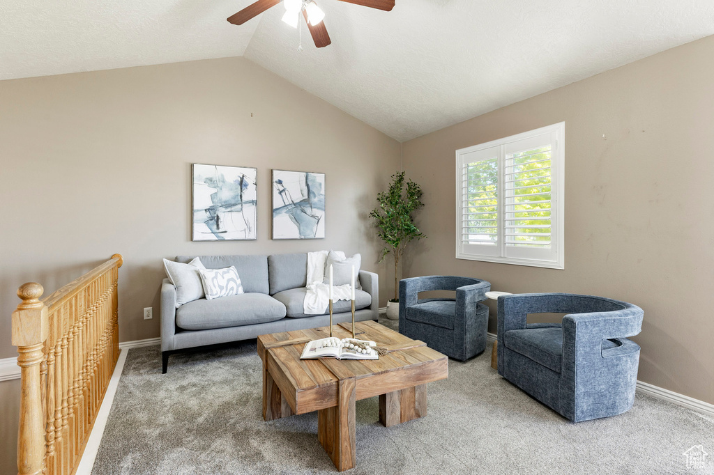 Living room with carpet, a ceiling fan, vaulted ceiling, and baseboards