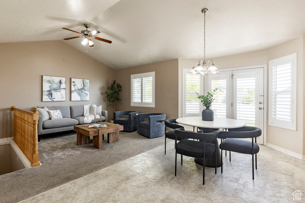 Dining space with vaulted ceiling, ceiling fan, a chandelier, baseboards, and light carpet