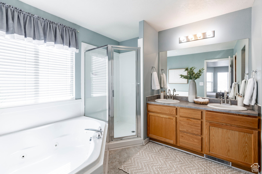 Full bath with a stall shower, double vanity, and a whirlpool tub