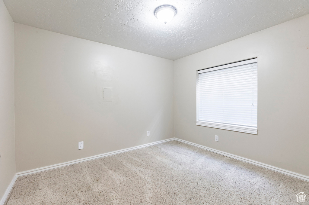 Carpeted spare room with baseboards and a textured ceiling