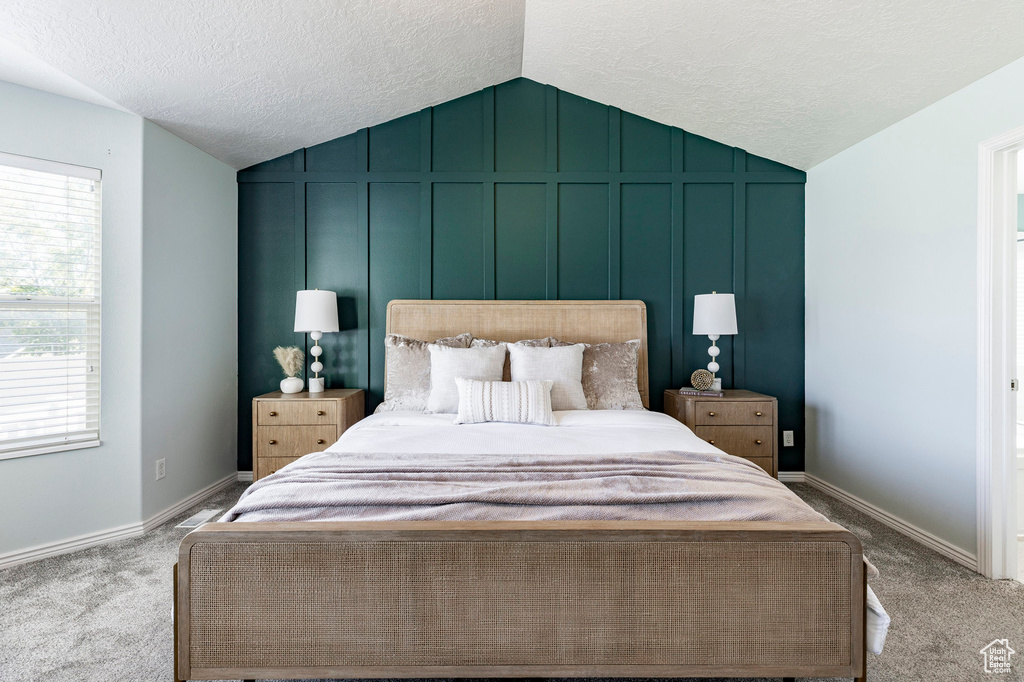 Bedroom featuring lofted ceiling, multiple windows, carpet, a textured ceiling, and baseboards