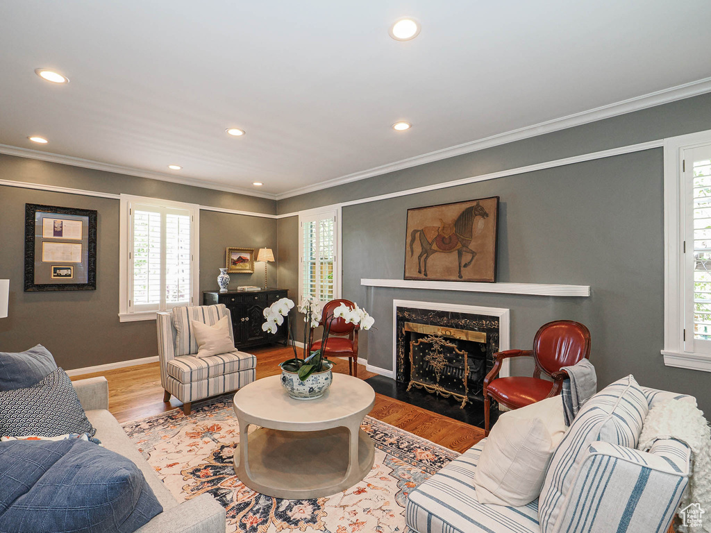 Living area featuring healthy amount of natural light, wood finished floors, a premium fireplace, recessed lighting, and ornamental molding