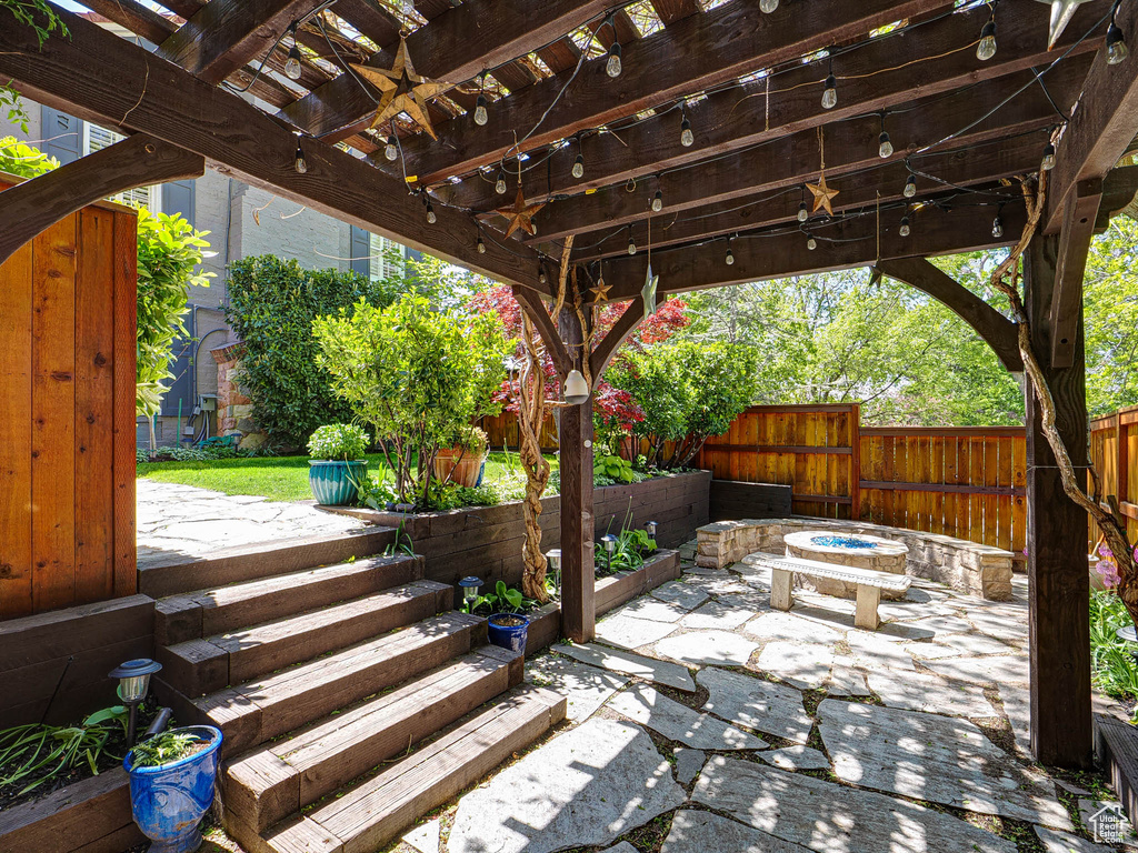 View of patio with a fire pit, a fenced backyard, a ceiling fan, and a pergola
