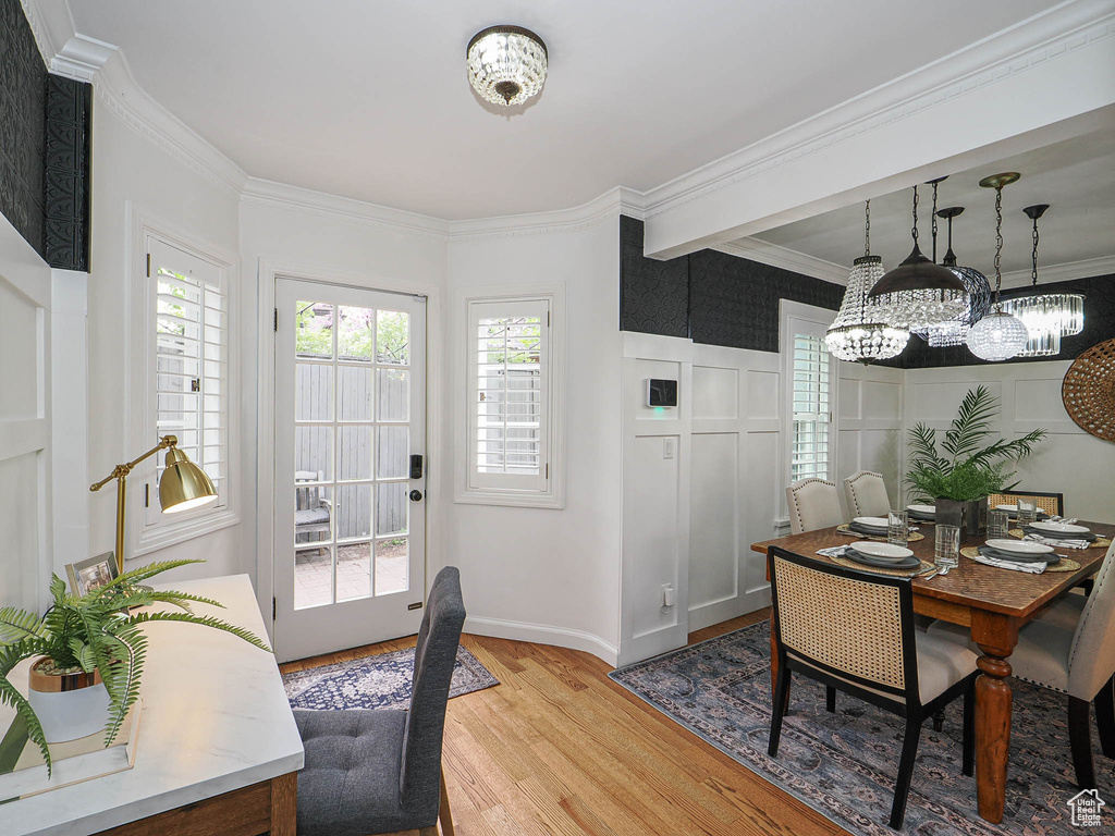 Dining space featuring light wood-type flooring, a chandelier, ornamental molding, and baseboards