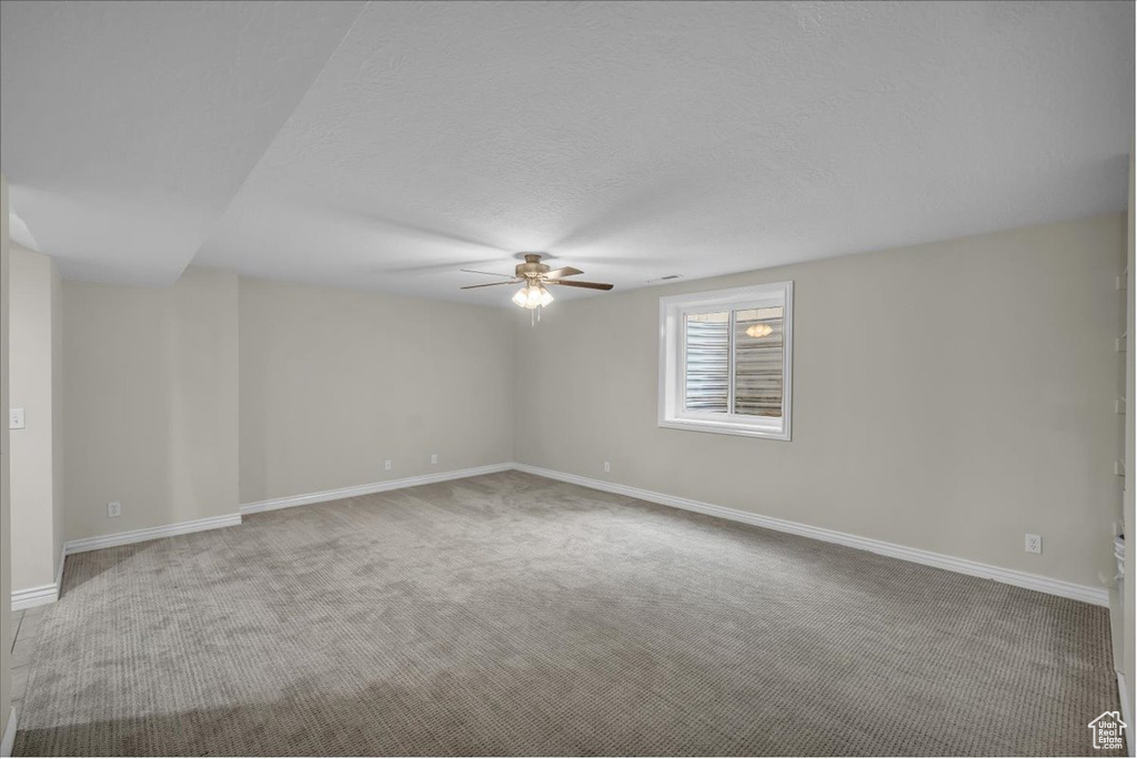 Unfurnished room with a ceiling fan, carpet flooring, baseboards, and a textured ceiling