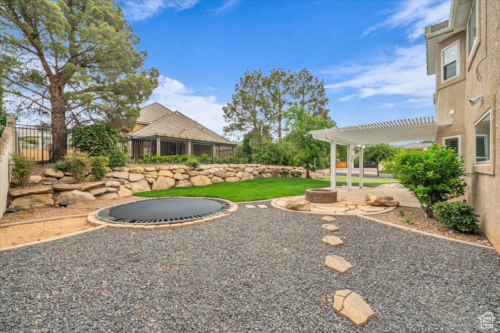 Fenced backyard with a pergola, an outdoor fire pit, and a patio area