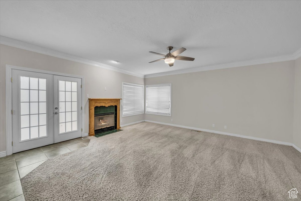 Unfurnished living room featuring ceiling fan, crown molding, french doors, baseboards, and a high end fireplace