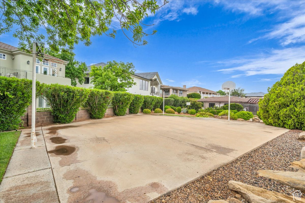 View of patio with a residential view, basketball hoop, and fence