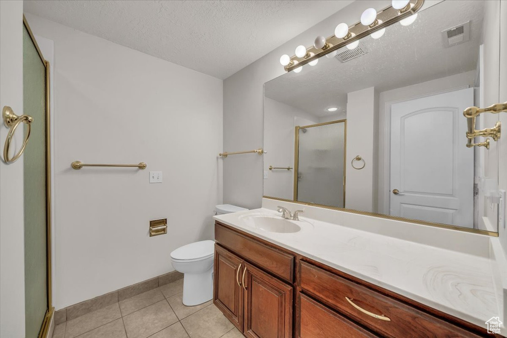 Full bath with a stall shower, tile patterned flooring, toilet, vanity, and baseboards