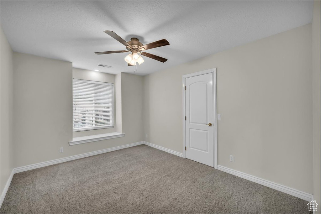 Empty room with carpet floors, a ceiling fan, baseboards, and a textured ceiling