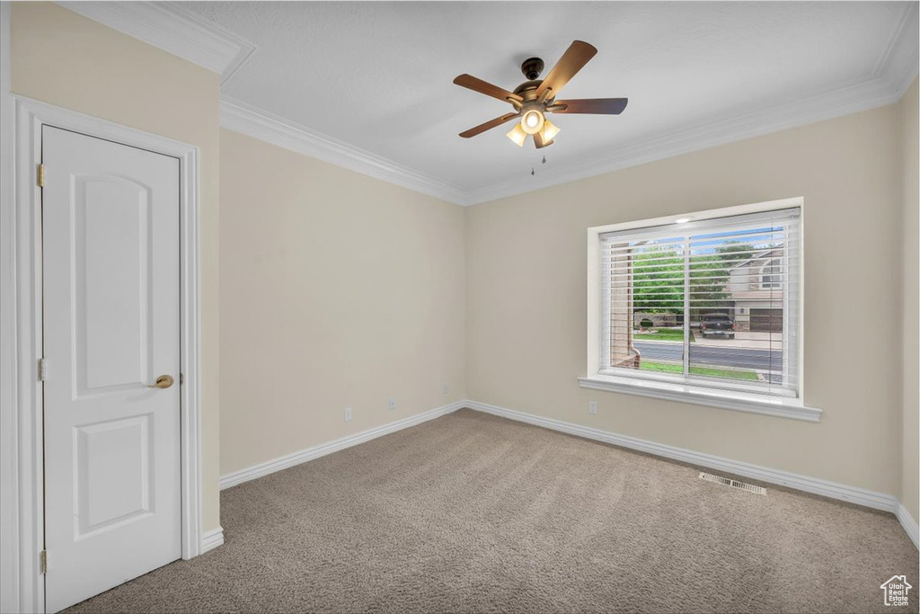 Carpeted spare room featuring ornamental molding, a ceiling fan, and baseboards