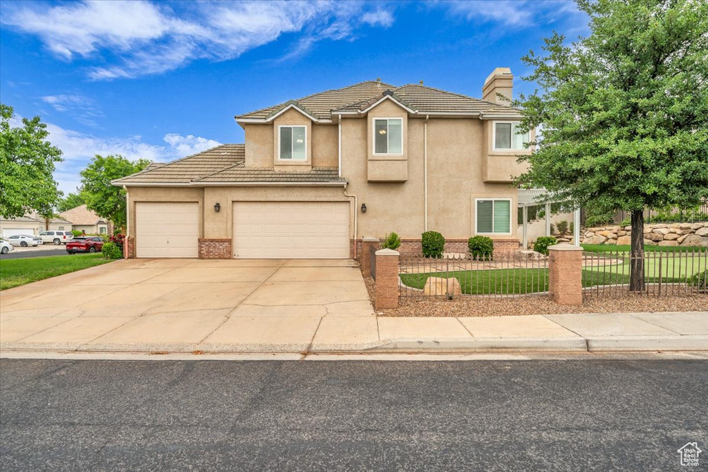 Traditional-style home with a chimney, driveway, stucco siding, and a tiled roof