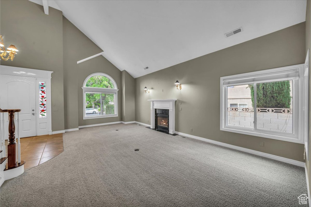 Unfurnished living room featuring high vaulted ceiling, carpet flooring, a fireplace, baseboards, and tile patterned floors