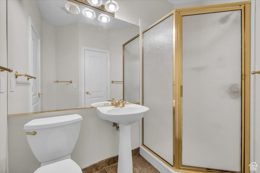 Bathroom featuring a shower stall, toilet, and tile patterned floors