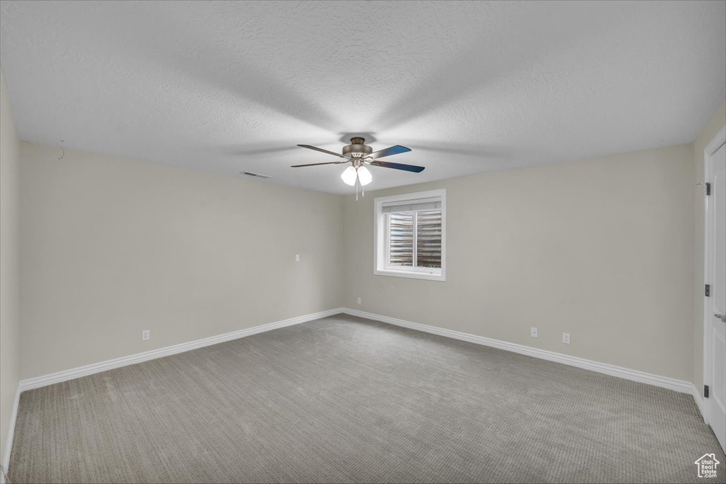 Unfurnished room featuring a ceiling fan, carpet, baseboards, and a textured ceiling