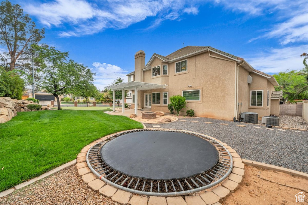 Rear view of house featuring a pergola, a patio, cooling unit, and a yard