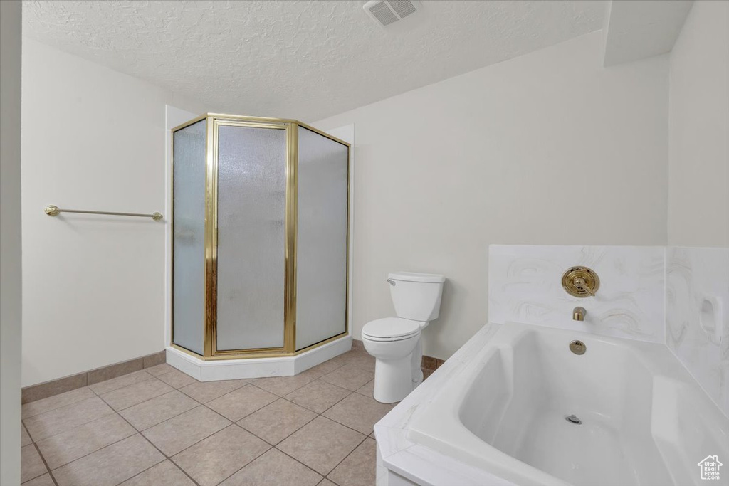 Full bathroom with a textured ceiling, baseboards, toilet, a shower stall, and a garden tub