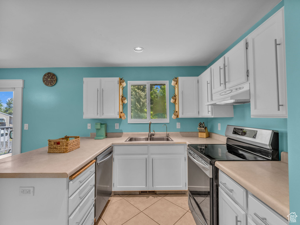 Kitchen with stainless steel appliances, a sink, under cabinet range hood, a peninsula, and white cabinets