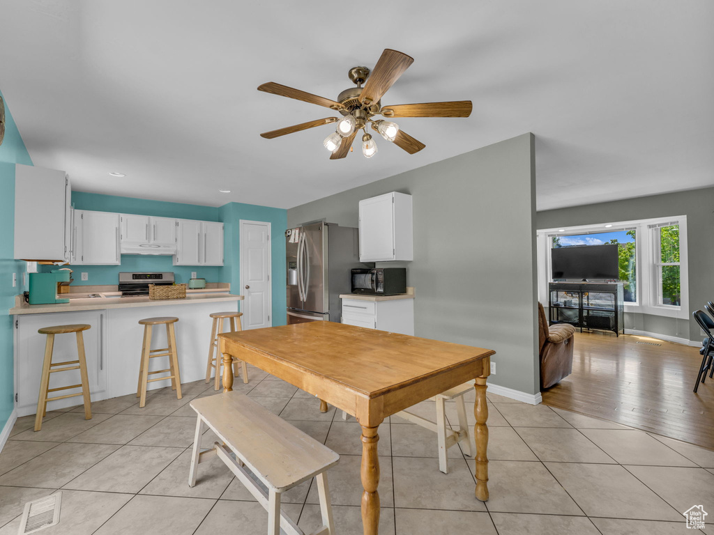 Dining space with a ceiling fan, baseboards, and light tile patterned floors
