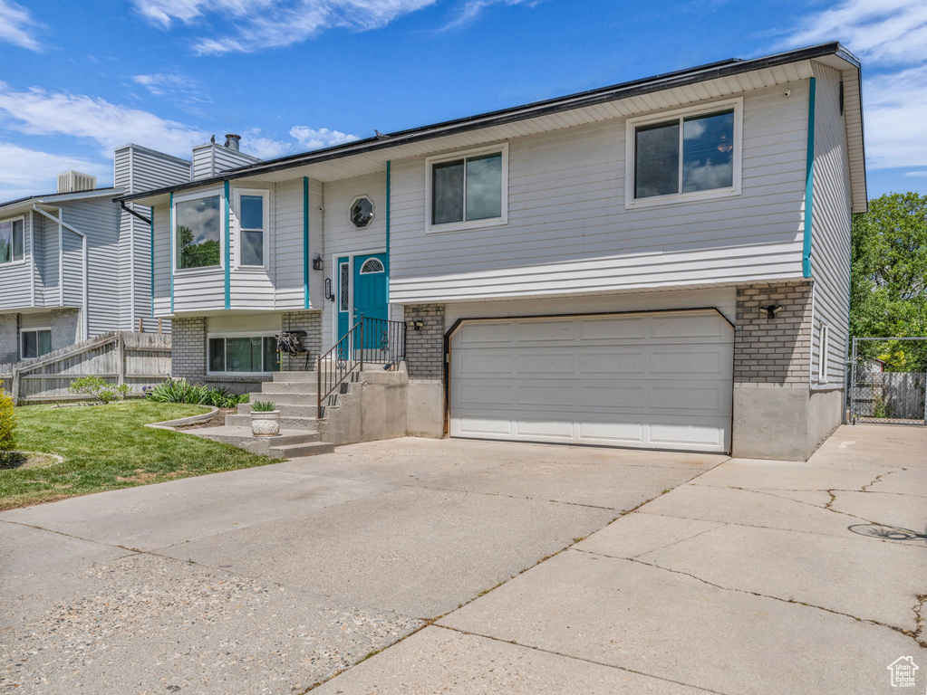 Raised ranch with brick siding, a garage, and driveway