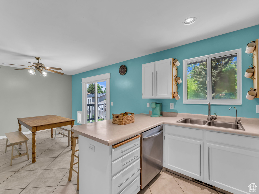 Kitchen with dishwasher, a sink, white cabinetry, a peninsula, and light countertops