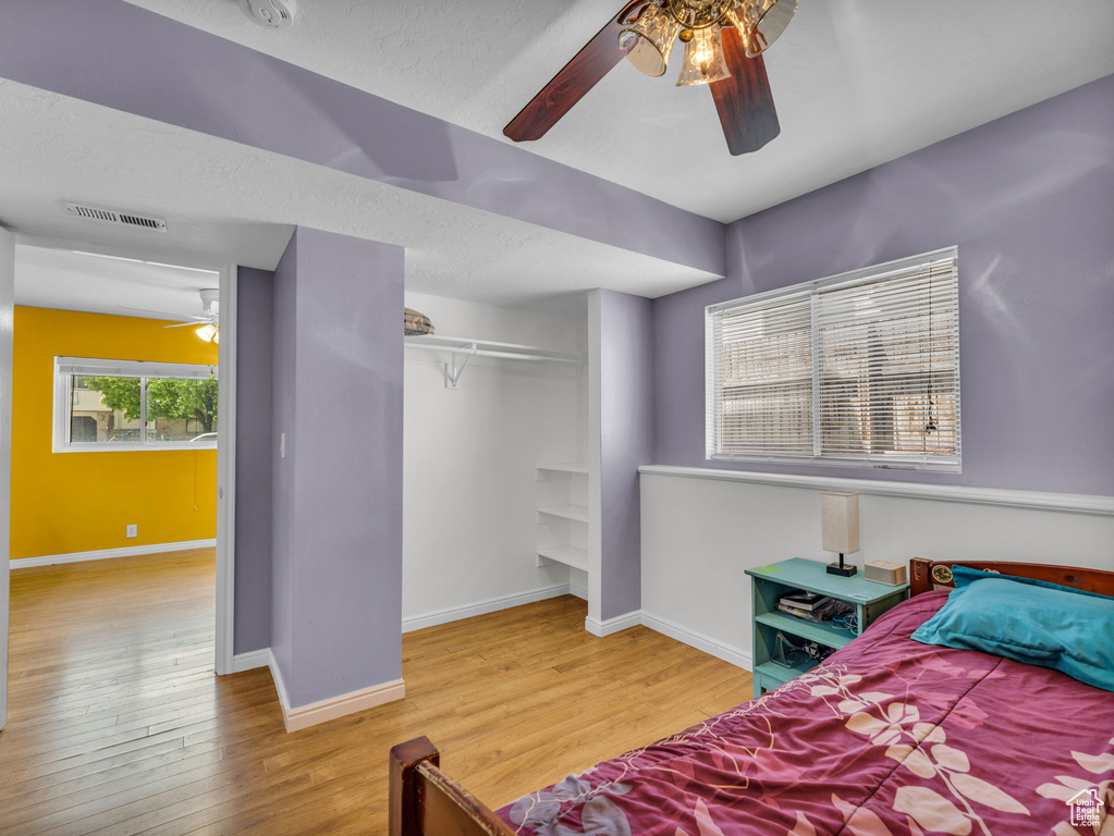 Bedroom featuring wood finished floors, baseboards, a closet, ceiling fan, and a textured ceiling