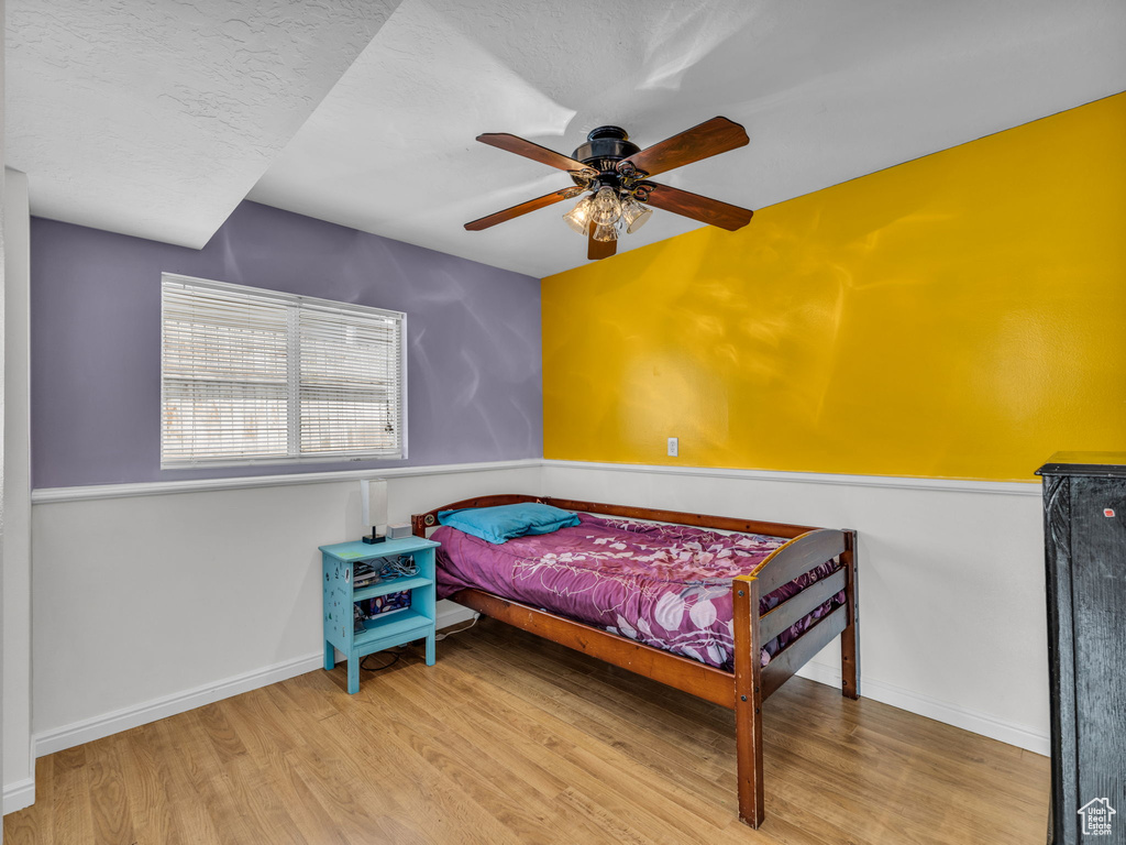 Bedroom with wood finished floors, a ceiling fan, and baseboards